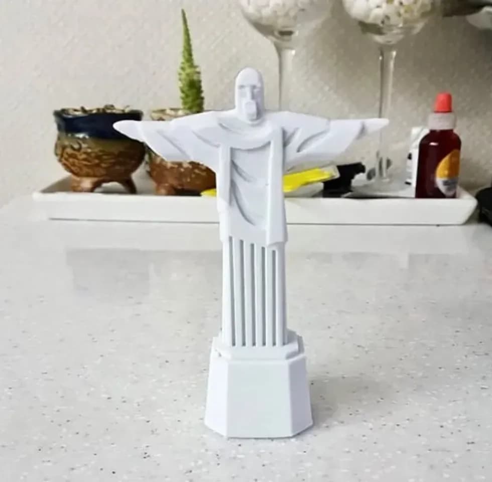 Estátua Cristo Redentor branca em ambiente decorado, mostrando escala