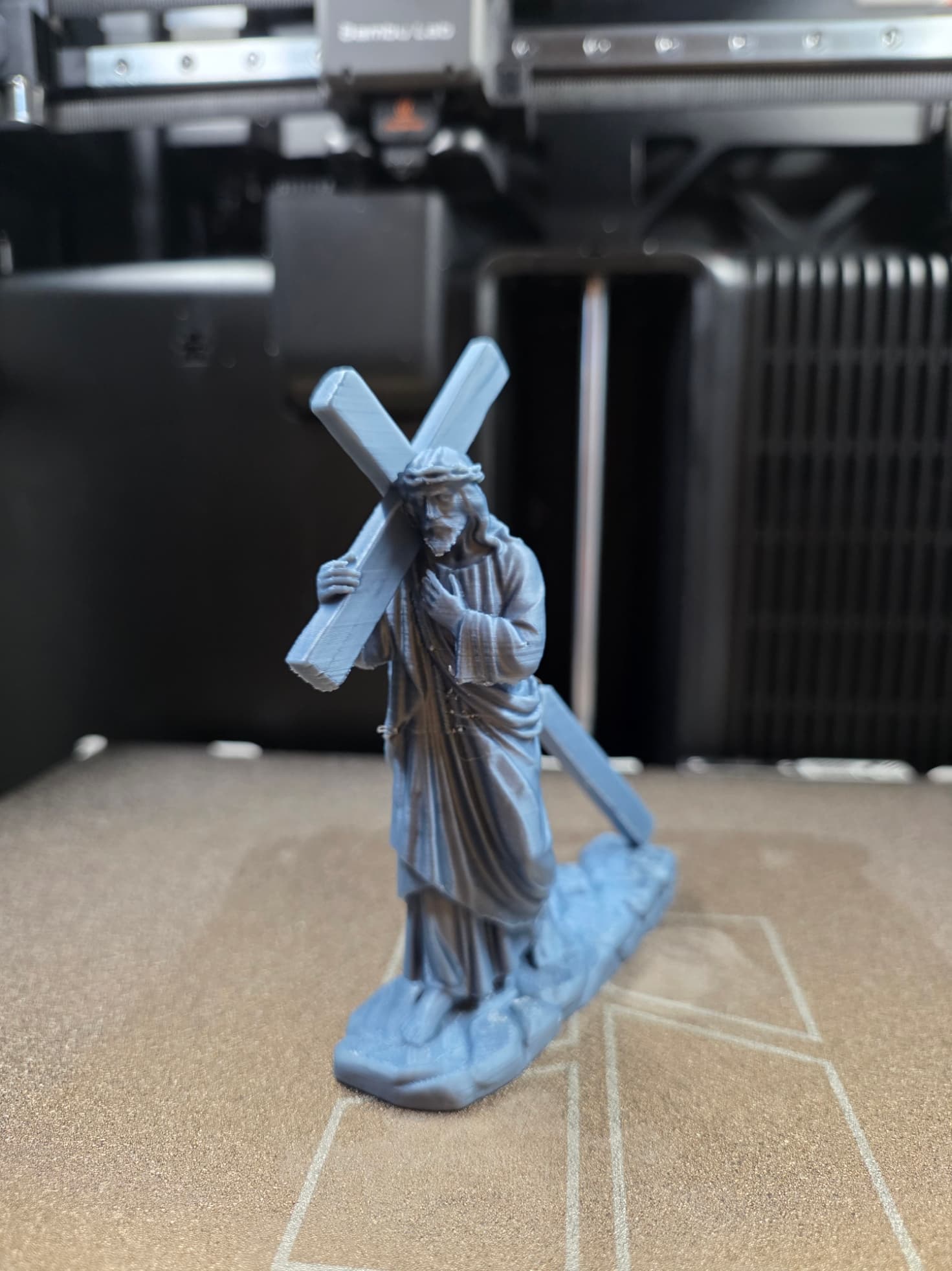 Estátua Cristo com a cruz vista frontal mostrando a túnica e a coroa de espinhos