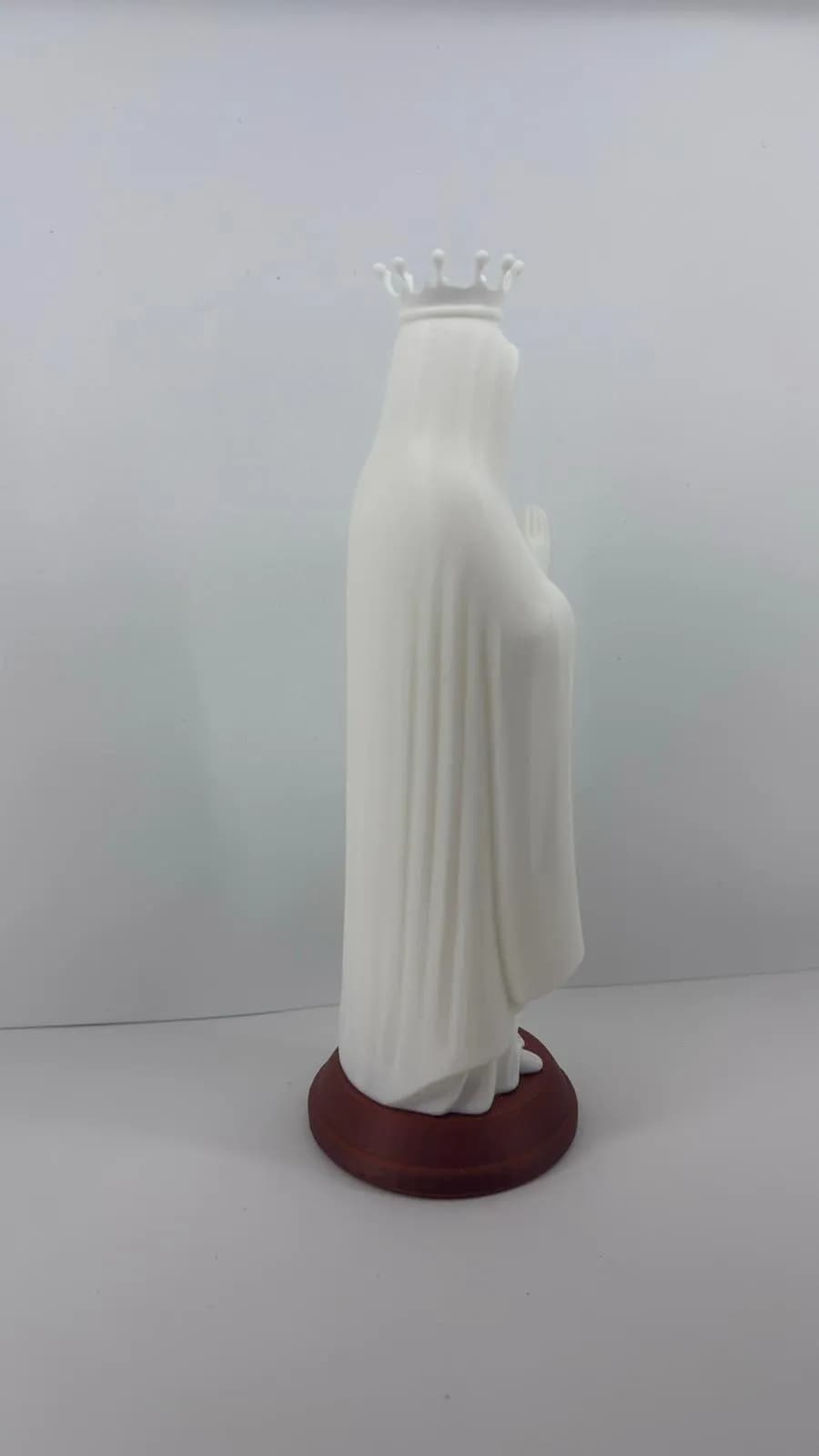 Vista lateral da escultura de Nossa Senhora de Fátima mostrando o manto fluido e a base terracota arredondada