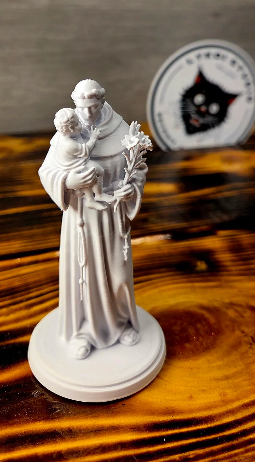 Escultura de Santo Antônio sobre mesa de madeira, mostrando detalhes do hábito, rosário e o Menino Jesus