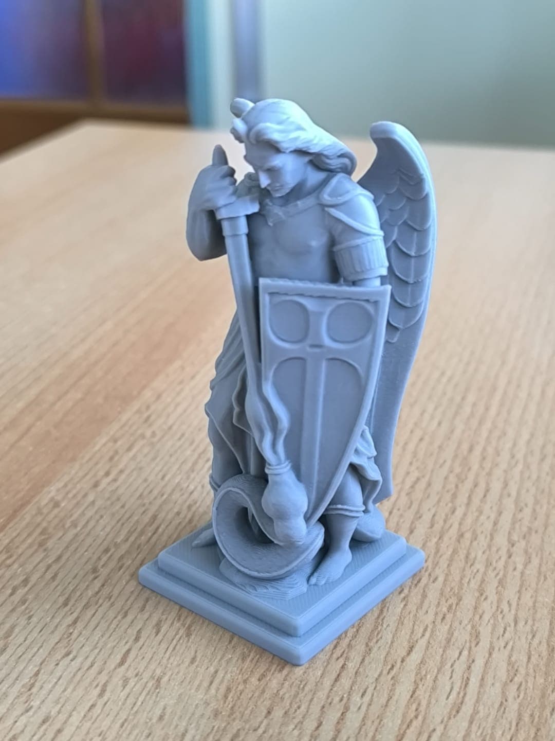 Vista frontal da escultura de São Miguel Arcanjo, detalhes das asas abertas, armadura e expressão de vitória